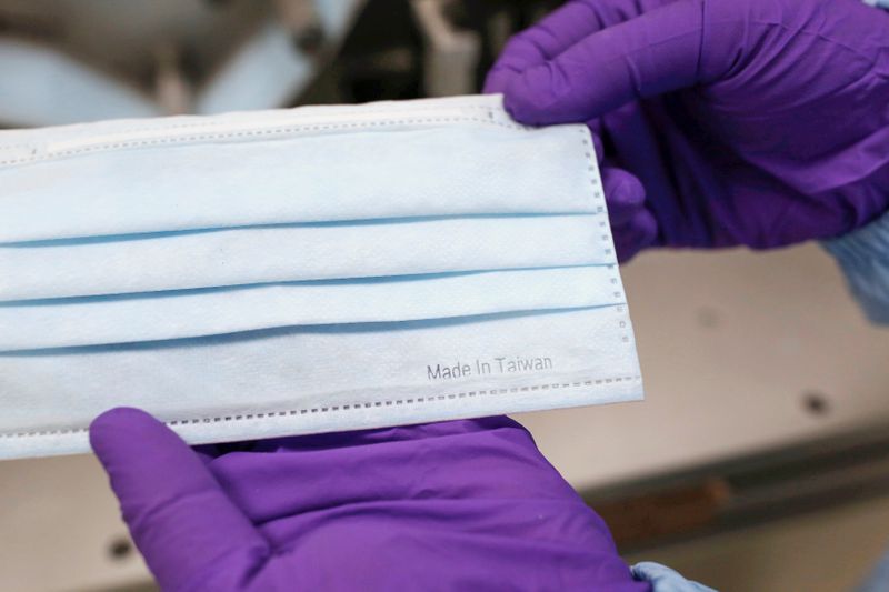 &copy; Reuters. Worker shows a surgical mask with &quot;Made in Taiwan&quot; mark from a production line in a factory in Taoyuan