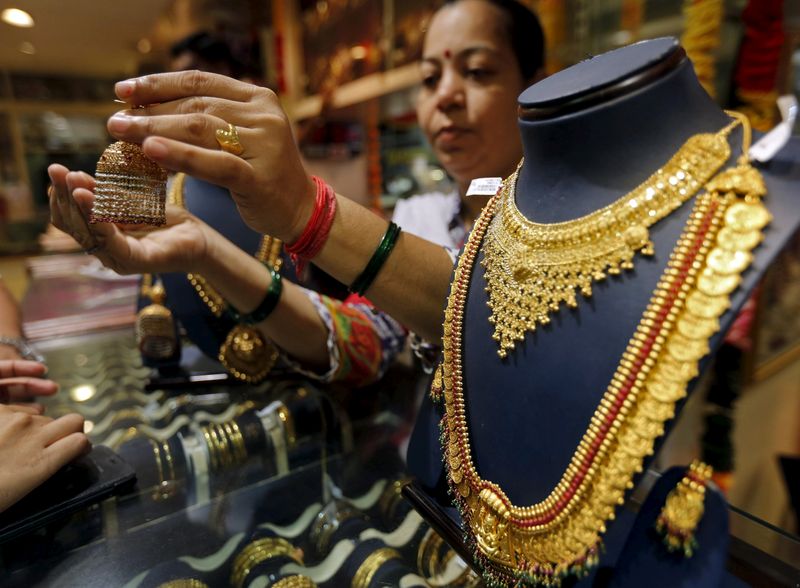 &copy; Reuters. FILE PHOTO: A saleswoman shows a gold earring to customers at a jewellery showroom in Mumbai