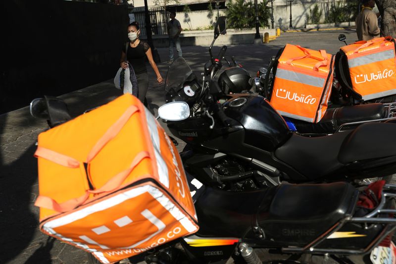 &copy; Reuters. Mulher com máscara de proteção passa por motos de entregadores em Caracas