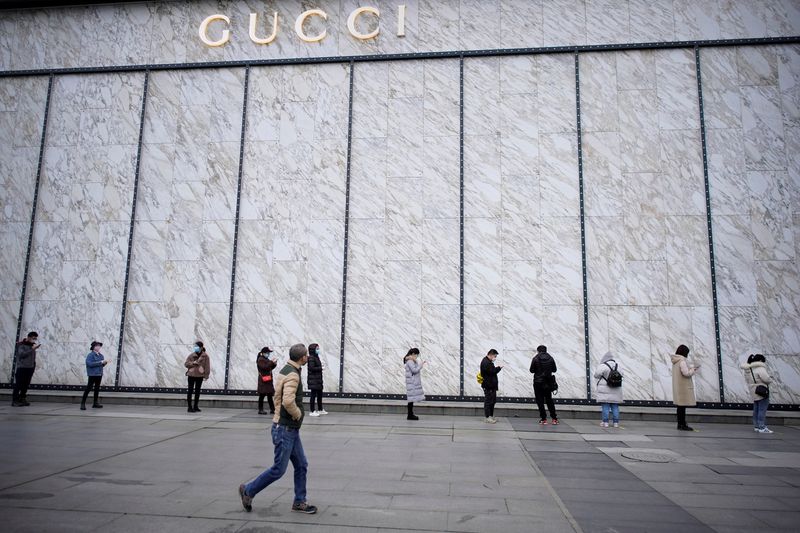 &copy; Reuters. FILE PHOTO: People wearing face masks line up to enter a shopping mall outside a Gucci store in Wuhan