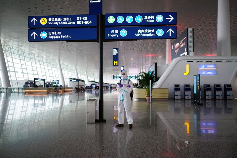 &copy; Reuters. FILE PHOTO:  Man in protective suit stands at Wuhan Tianhe International Airport in Wuhan