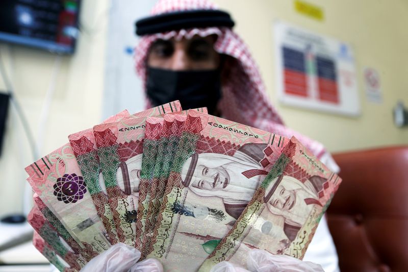 &copy; Reuters. FILE PHOTO: A Saudi money exchanger wears a protective face mask and gloves, as he counts Saudi riyal currency at a currency exchange shop in Riyadh