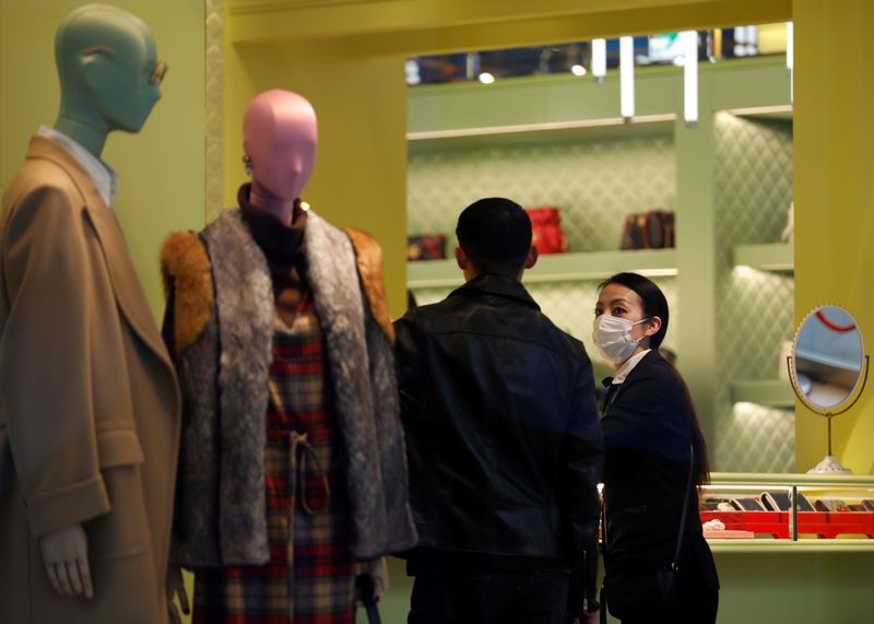 © Reuters. FILE PHOTO: A shop assistance wearing a protective face mask following an outbreak of the coronavirus talks to a customer at shopping mall in Tokyo