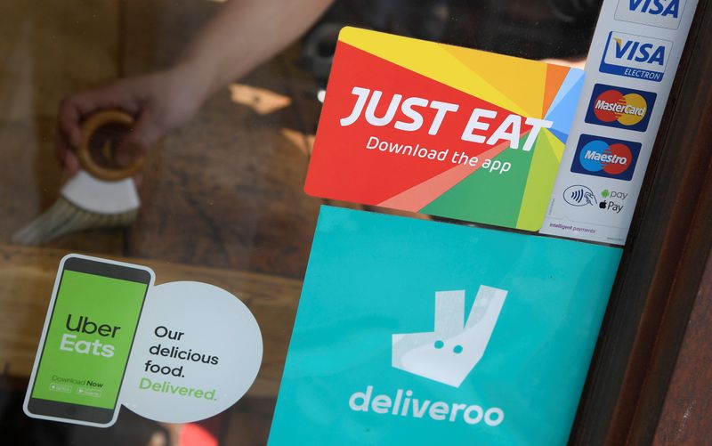 &copy; Reuters. FILE PHOTO:  Signage for Just Eat is seen next to Uber Eats and Deliveroo advertisements on the window of a restaurant in London