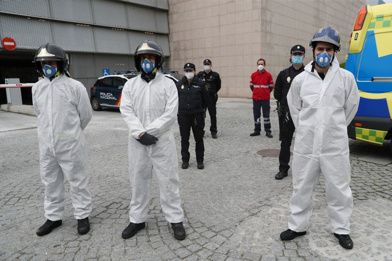 &copy; Reuters. Bombeiros e policiais com trajes de proteção fazem um minuto de silêncio em Segovia, na Espanha