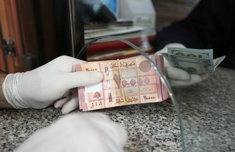 © Reuters. Un cliente con guantes tiene libras libanesas en una tienda de cambio de moneda en Beirut