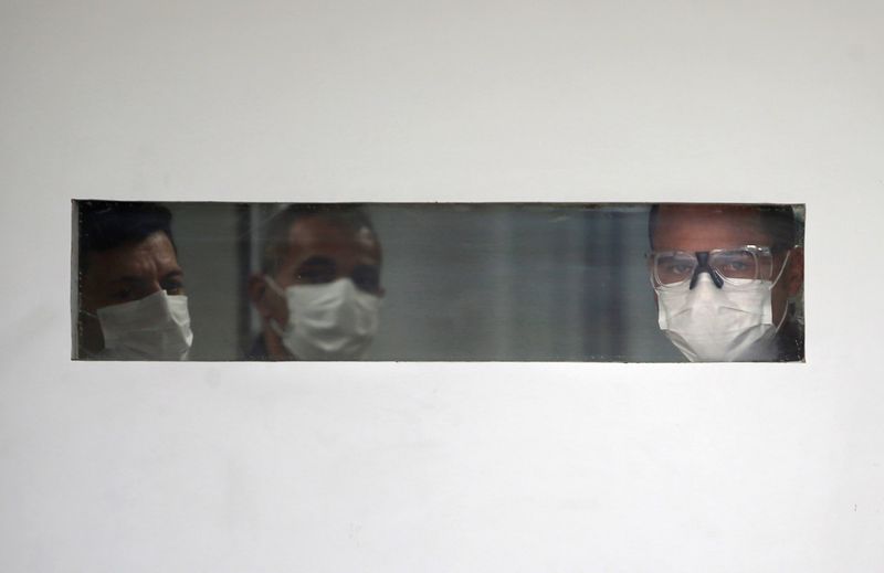 &copy; Reuters. Homens com máscara olham por janela de hospital em São Paulo