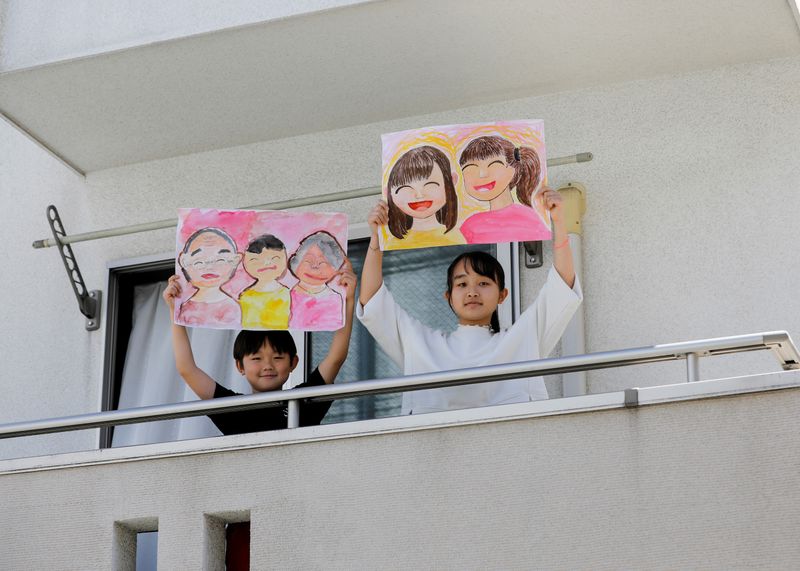 &copy; Reuters. Foto de Reku Matsui, de 8 años, y Yaya Matsui, de 12, posando con los dibujo que hicieron en medio del confinamiento por la pandemia de coronavirus, en el balcón de su casa en Tokio