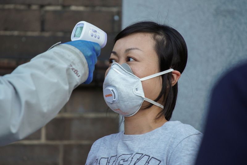 &copy; Reuters. Le toman la temperatura a una voluntaria de la iglesia como medida de precaución durante la propagación de la enfermedad del coronavirus (COVID-19), en Sydney