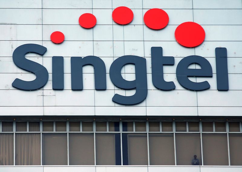 &copy; Reuters. FILE PHOTO A man looks out of the window under a Singtel signage at their head office in Singapore