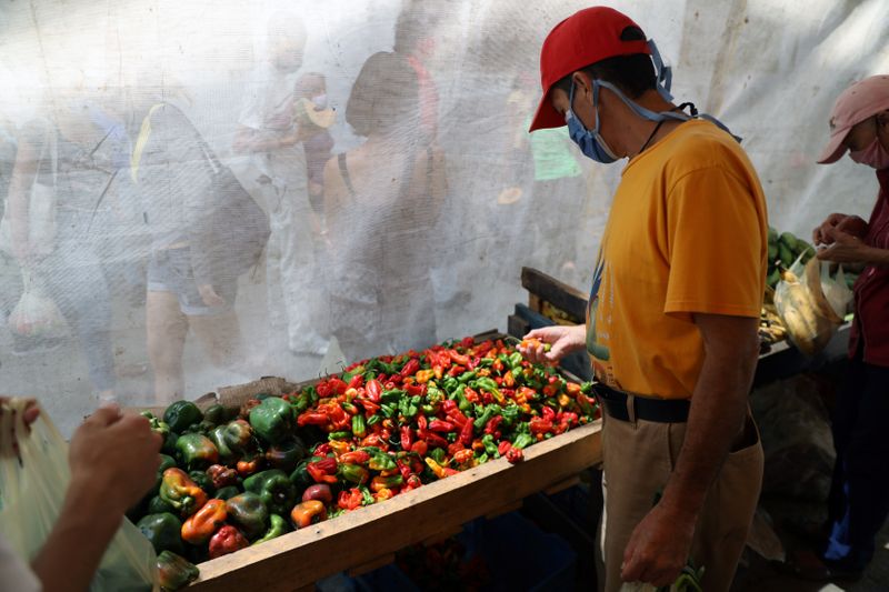 &copy; Reuters. A man wearing protective mask is seen shopping at a vegetables street market during the nationwide quarantine as coronavirus disease (COVID-19) continues in Caracas