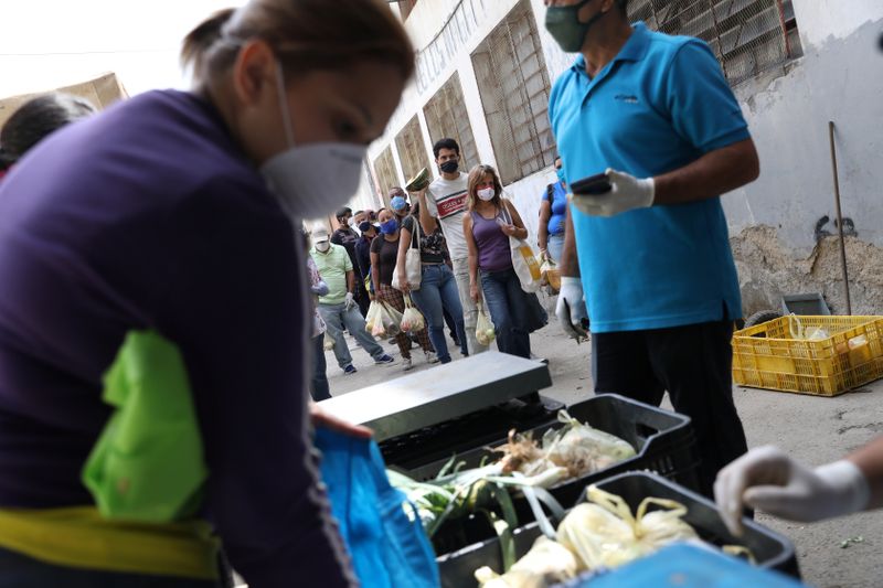 © Reuters. People wearing protective masks line up at a vegetables street market during the nationwide quarantine as coronavirus disease (COVID-19) continues in Caracas