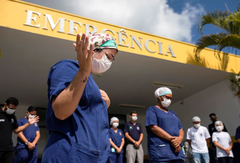 &copy; Reuters. Profissionais de saúde rezam em frente a hospital em lhabela, lotoral de São Paulo