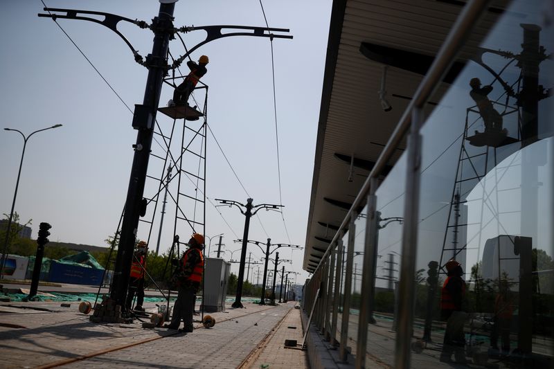 &copy; Reuters. Trabajadores con equipo protector arreglan un cable de tranvía en Pekín