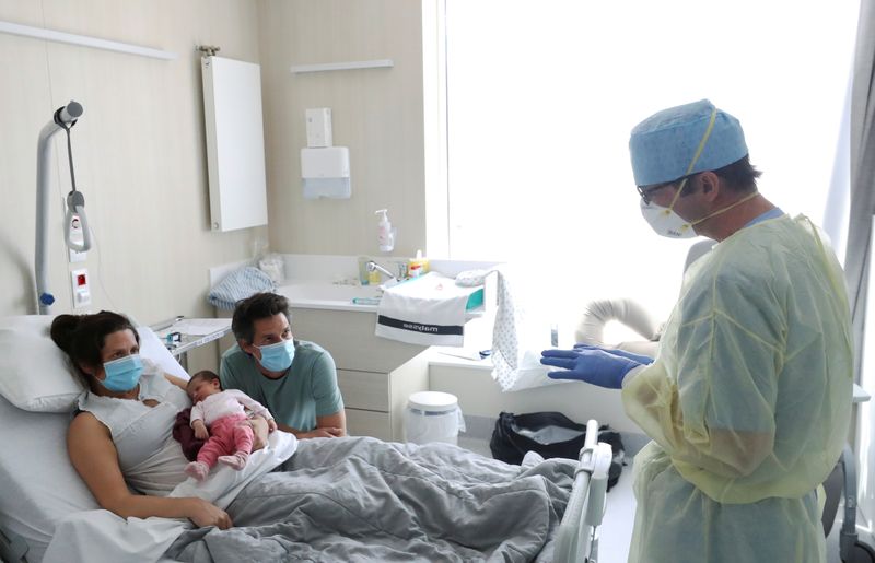 &copy; Reuters. Amandine, who tested positive for the coronavirus disease (COVID-19) just before giving birth, wearing a protective face mask is pictured with her newborn daughter Mahaut at the maternity at CHIREC Delta Hospital in Brussels