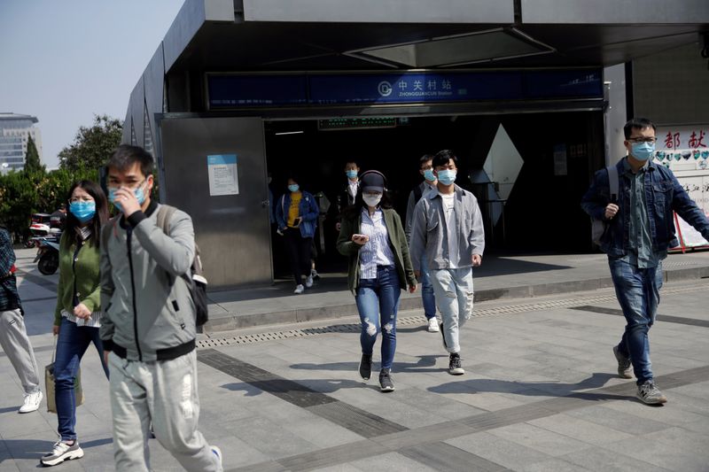 &copy; Reuters. People wearing face masks walk out of Zhongguancun subway station in Beijing