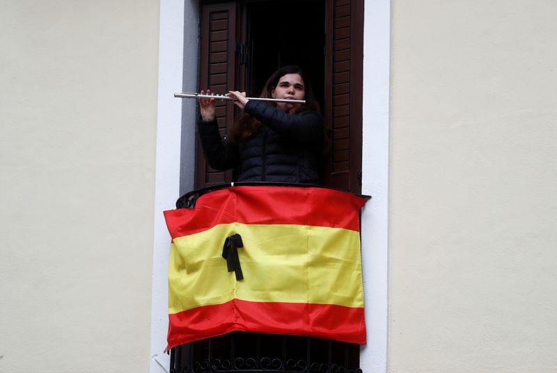 © Reuters. Mulher toca flauta em varanda durante pandemia de coronavírus em Ronda, na Espanha