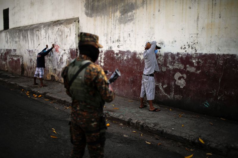 © Reuters. Policial militar monitora homens detidos durante operação ordenada pelo presidente Nayib Bukele