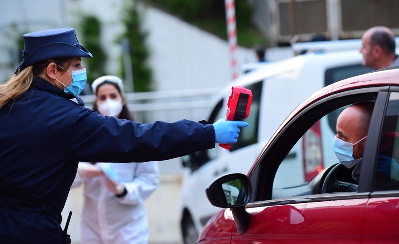 © Reuters. Un'impiegata controlla la temperatura di un guidatore che entra nello stabilimento Fca Mirafiori a Torino