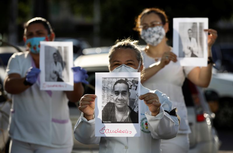 &copy; Reuters. Profissionais de saúde com roupa de proteção prestam homenagem a colegas mortos pelo novo coronavírus em Manaus