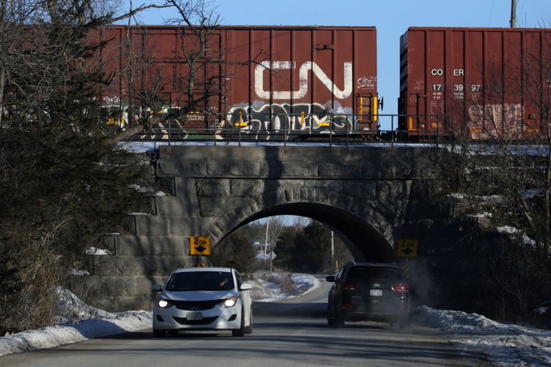 © Reuters. Car passes through a tunnel under a Canadian National Railway (CN Rail) train, halted near a Tyendinaga Mohawk Territory camp