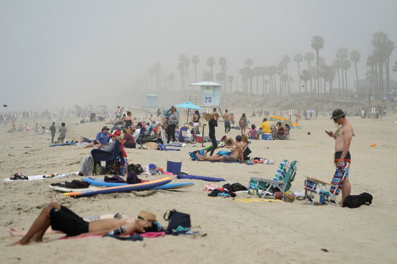 &copy; Reuters. FOTO DE ARCHIVO: Gente sentada en grupos en Huntington City Beach durante el brote de la enfermedad coronavirus (COVID-19) en Huntington Beach, California