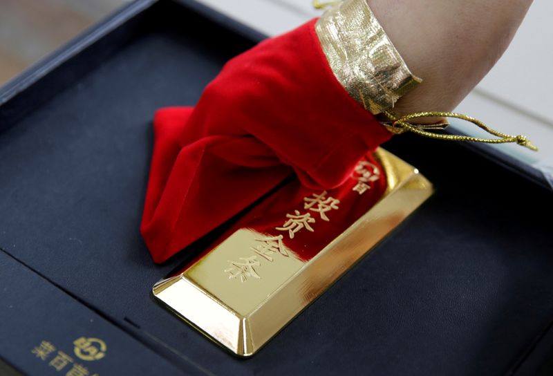 &copy; Reuters. FILE PHOTO: A sales assistant displays a 1000 gram gold bar as an investment for a customer at Caibai Jewelry store in Beijing