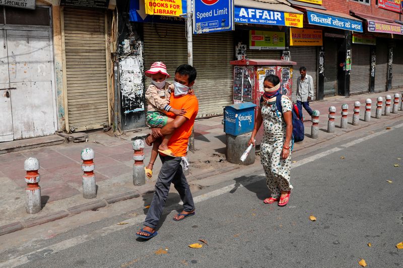 © Reuters. Pessoas com máscara de proteção contra coronavírus caminham pelas ruas de Nova Délhi, Índia