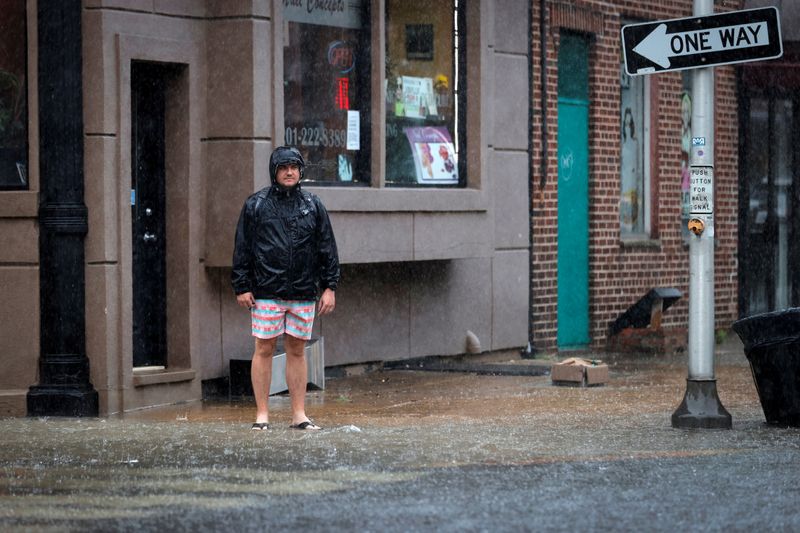 &copy; Reuters. A man stands in a flooded street as Tropical Storm Fay sweeps across the heavily populated northeastern United States in Hoboken