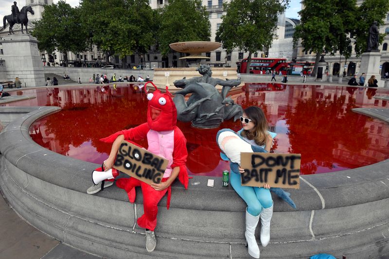 &copy; Reuters. Animal rights activists hold signs as they sit at a fountain whose water was turned red after protesters poured coloured dye into the clear water, on Trafalgar Square in London