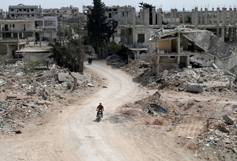 &copy; Reuters. FILE PHOTO: A man rides a motorbike past damaged buildings in the rebel-held town of Nairab