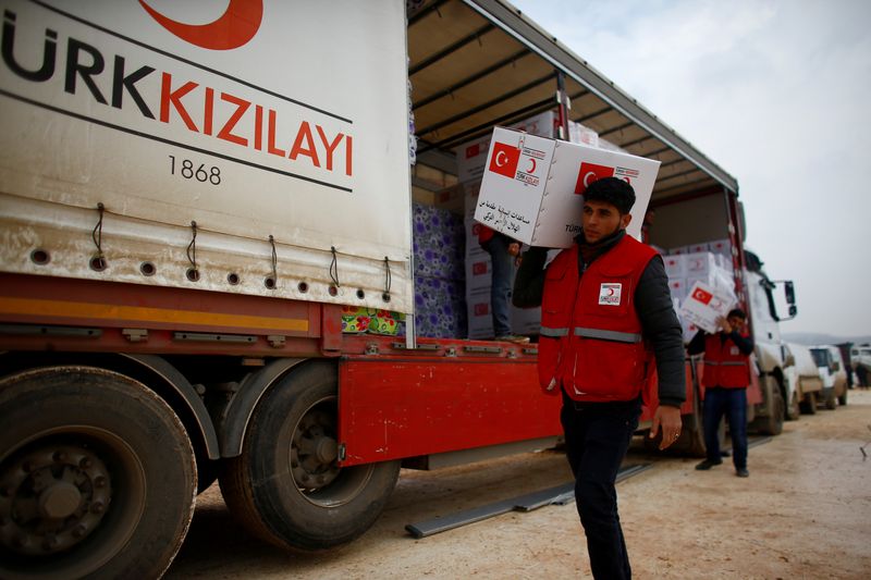 © Reuters. FILE PHOTO: Turkish Red Crescent workers carry humanitarian aid at Kelbit camp in Idlib province