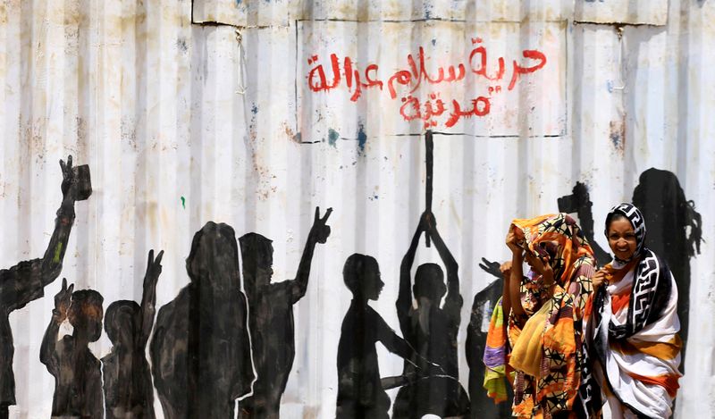 © Reuters. FILE PHOTO: Civilians walk past graffiti reading in Arabic 