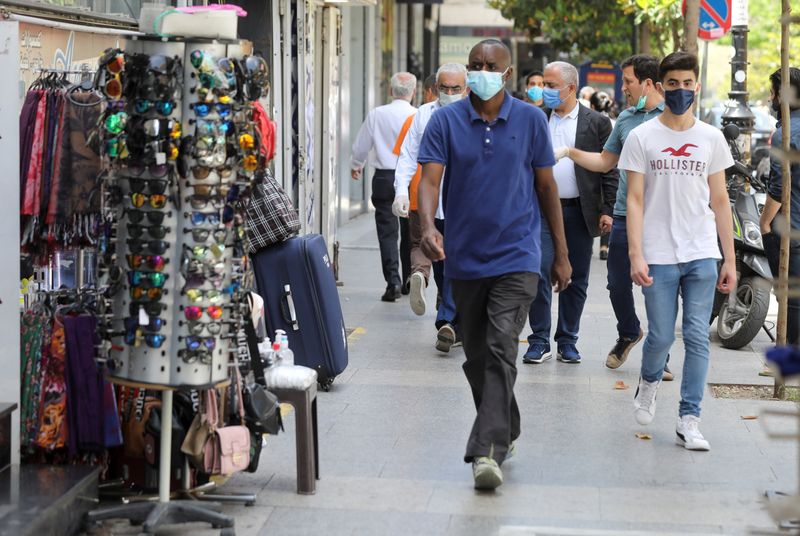 &copy; Reuters. People wearing protective face masks walk past open shops in Hamra street in Beirut