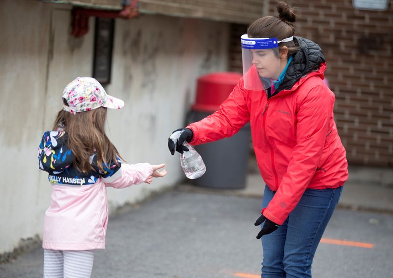 &copy; Reuters. FILE PHOTO: A student has hands sanitized in the schoolyard as schools reopen outside the greater Montreal region in Saint-Jean-sur-Richelieu