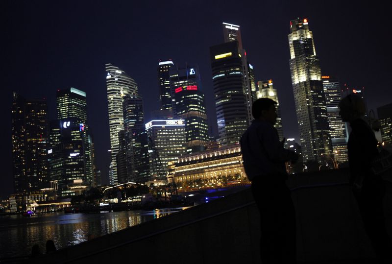 &copy; Reuters. FILE PHOTO: People chat as the skyline of Singapore&apos;s financial district is seen in the background