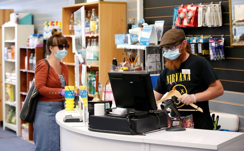 &copy; Reuters. FILE PHOTO: An employee wearing a protective face mask serves a customers at Willen Hospice charity shop as it is re-opening for all customers after previously being open only for NHS employees, keyworkers and the elderly, following the coronavirus diseas