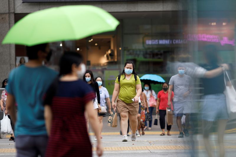 © Reuters. People wearing protective face masks cross a street in Singapore