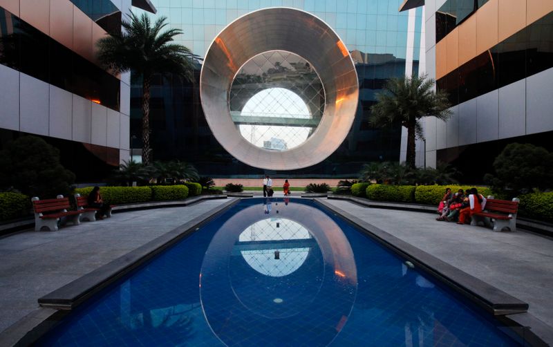 &copy; Reuters. Employees walk in front of a building dubbed the &quot;washing machine&quot;, a well-known landmark built by Infosys at the Electronics City IT district in Bangalore