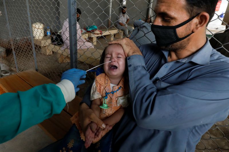 &copy; Reuters. Paramédico em trajes de proteção coleta amostra de bebê para exame de detecçã de  Covid-19 em Karachi, no Paquistão