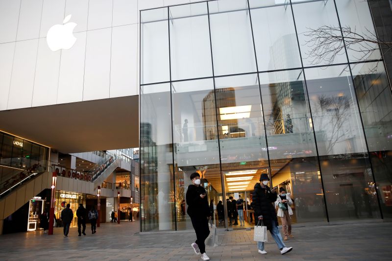 &copy; Reuters. FILE PHOTO: People wearing face masks walk in front of an Apple store at a shopping mall, as the country is hit by an outbreak of the new coronavirus, in Beijing