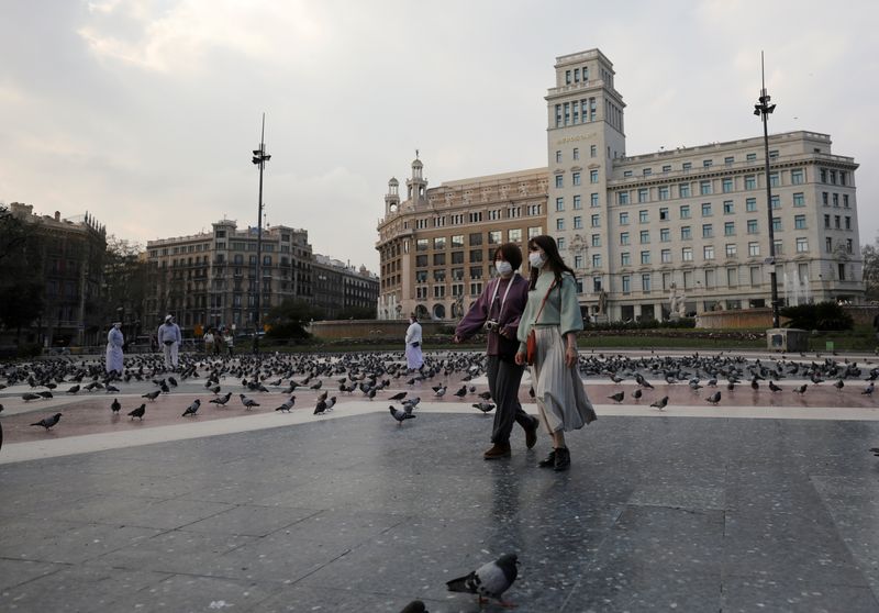 &copy; Reuters. FILE PHOTO: Women wear protective face masks as they walk through an empty Plaza de Catalunya (Catalonia Square), amidst concerns over coronavirus outbreak, in Barcelona