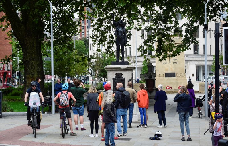 © Reuters. People looks at the sculpture of a Black Lives Matter protester standing on the empty plinth previously occupied by the statue of slave trader Edward Colston, in Bristol