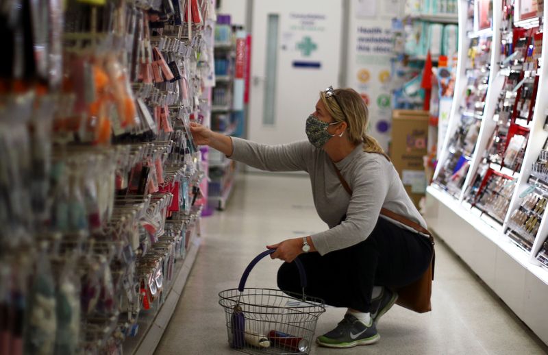© Reuters. FILE PHOTO: A woman wearing a protective face mask is seen in a shop, in London