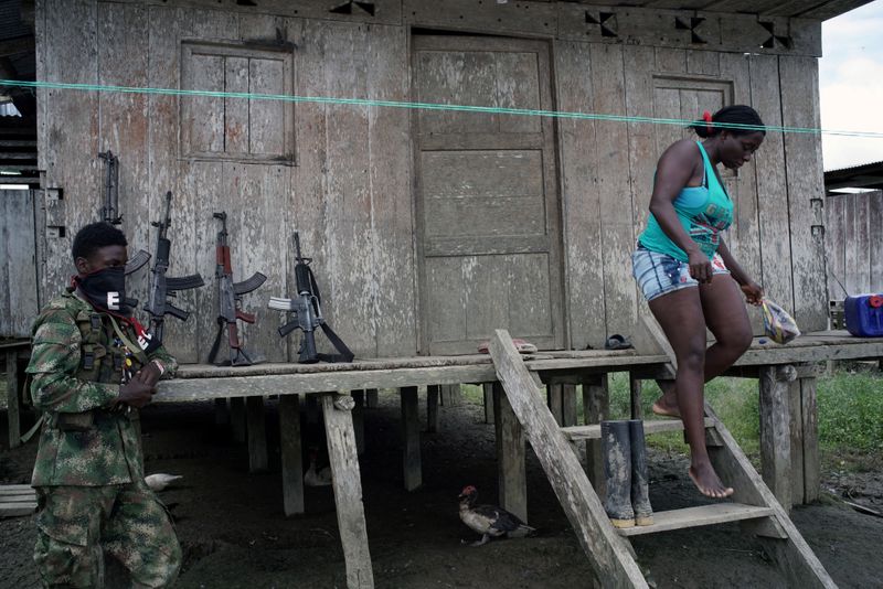 © Reuters. Foto de archivo. Una mujer baja las escaleras de su casa mientras un rebelde del Ejército de Liberación Nacional (ELN) descansa en las selvas del departamento del Chocó