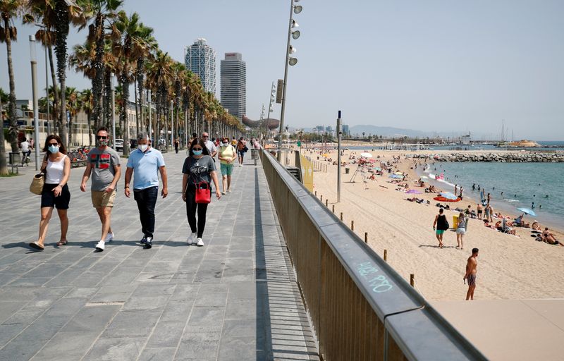 &copy; Reuters. Gente con mascarillas en la playa de la Barceloneta, en Barcelona