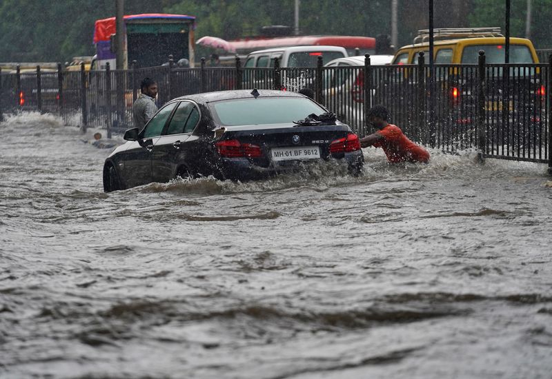 &copy; Reuters. Homem empurra carro em rua inundada em Mumbai