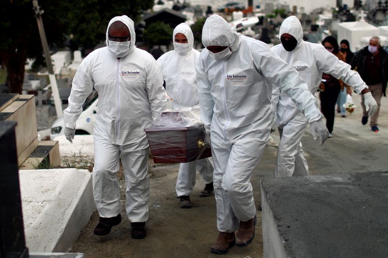 &copy; Reuters. Funcionários de cemitério com roupa de proteção durante enterro de vítima da Covid-19 em Nova Iguaçu (RJ)