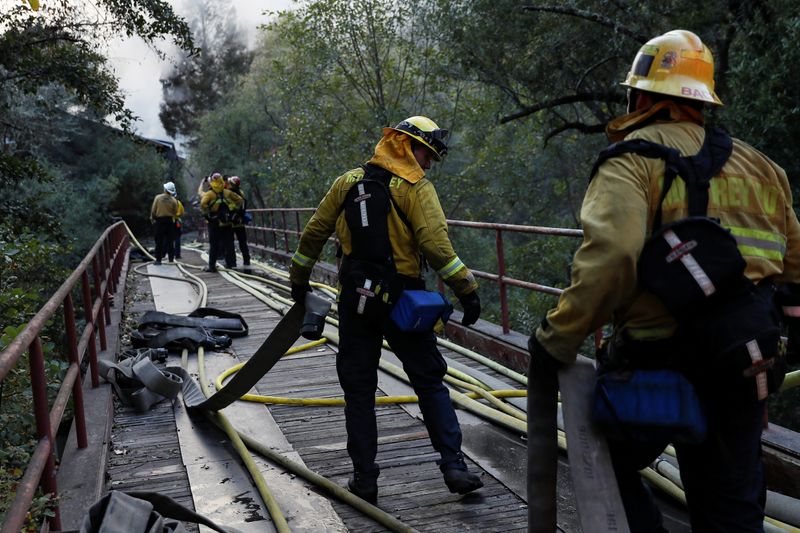 &copy; Reuters. A firefighter works with a hose while working on a burning structure during the Kincade fire in Calistoga, California