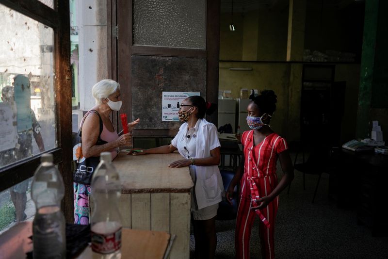 &copy; Reuters. Yeni Montesinos (centro) habla con una cliente en una farmacia en La Habana, Cuba.